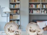 two cups and saucers sitting on a table in front of a bookshelf