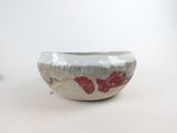 a white bowl with red designs on it on a table