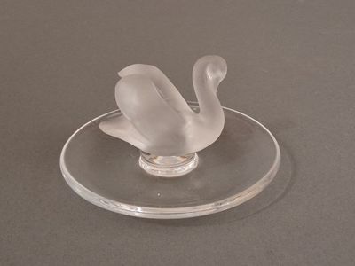 a clear glass swan on a clear plate on a table