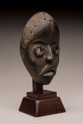 un gros plan sur une sculpture représentant un visage, posée sur un socle en bois