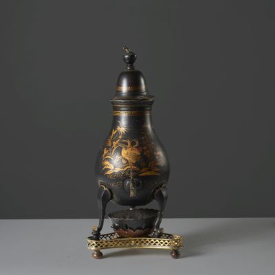 a black and gold vase sitting on top of a metal stand