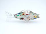 sculpture de poisson en verre posée sur une surface blanche, avec un fond blanc