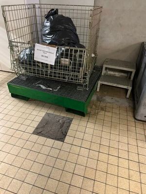 un panier en métal sur lequel est accrochée une pancarte, dans une pièce