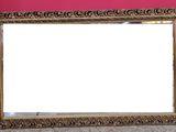 an ornate gold frame with a white background and a pink wall