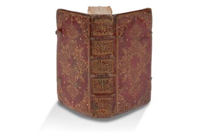 un vieux livre à la couverture rouge posé sur une surface blanche