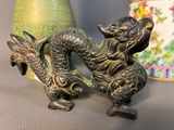 a statue of a dragon on a table next to a vase