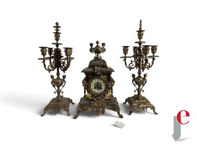 three candles and a clock sitting on a table
