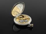 silver and gold pocket watch on a black surface with reflection