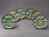 five green and brown plates with designs on them on a gray surface