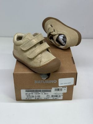 des chaussures de bébé dans une boîte posée sur une surface blanche