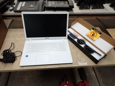 un ordinateur portable posé sur un bureau, à côté d'autres appareils électroniques