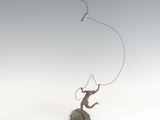 a statue of a man on a rock flying a kite