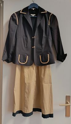 une veste noire et une jupe beige accrochées au mur