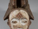 a close up of a wooden mask on a white surface