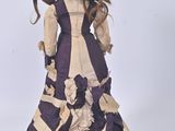 a doll that is wearing a purple and white dress
