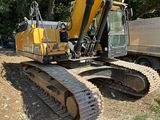 une photo d'une pelleteuse jaune et noire sur un terrain en terre battue