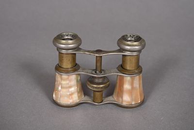 pair of antique brass and mother of pearl binoculars on grey background