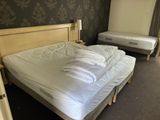 a bed with white sheets and pillows in a bedroom