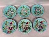 six assiettes bleues ornées d'oiseaux et de baies, posées sur une table