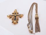 a close up of a cross and a tassel on a white surface