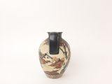a small vase with a painting on it on a white surface