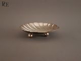un plateau en argent orné d'une feuille, posé sur une table