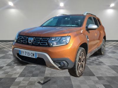 La Dacia orange est garée sur un sol en carrelage à damier.