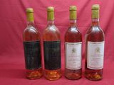 four bottles of wine are lined up on a pink background