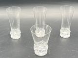 four glasses sitting on a table with a black background