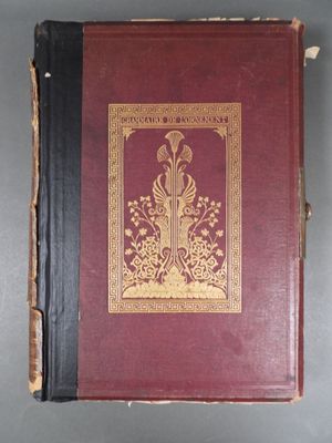an old book with a red cover sitting on top of a table