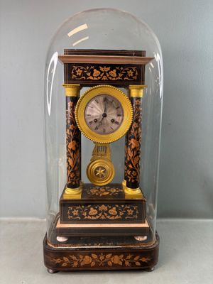 une petite horloge sous un dôme de verre sur une table