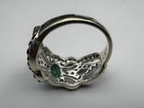 a close up of a silver ring with a green stone in it