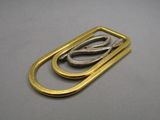 two pairs of scissors are sitting on top of a gold plated paper clip