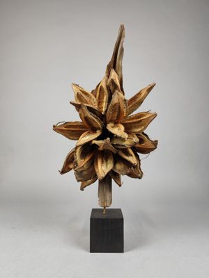 sculpture représentant une fleur sur un socle en bois, sur fond blanc