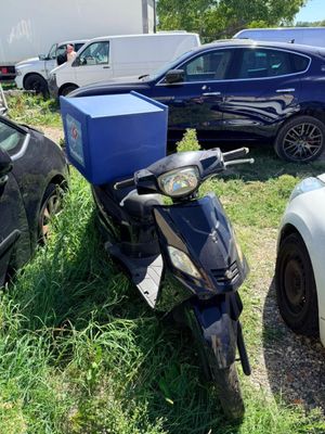 un scooter garé dans l'herbe à côté d'autres voitures