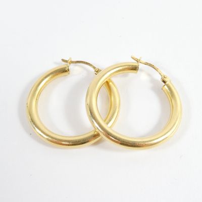 deux paires de boucles d'oreilles créoles en or sur fond blanc