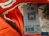 an orange jacket with a price tag on it sitting on top of a table