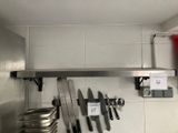 une photo d'une cuisine où l'on voit plusieurs couteaux accrochés au mur