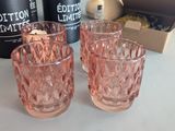two pink glasses sitting on a table next to a bottle of wine