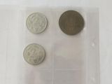three coins in a plastic container on a white surface