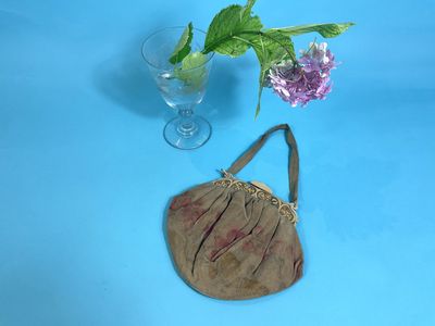 a small purse sitting next to a vase with a flower in it