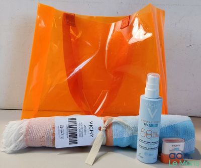 un sac orange contenant une serviette, un flacon de crème solaire et un flacon de crème solaire
