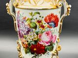 a vase with flowers painted on it sitting on a table