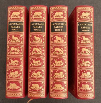 trois livres rouges ornés d'illustrations dorées, posés sur une table