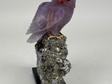 a purple bird sitting on top of a rock on a white surface