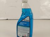 un gros plan d'un flacon bleu de produit nettoyant posé sur une surface blanche