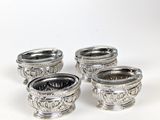quatre bols en métal argenté, ornés de motifs sur un fond blanc