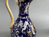 a blue and white pitcher with a gold decoration on it