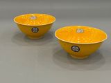 pair of yellow bowls with silver decoration on the rim
