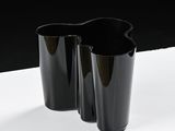 two black vases on a white table with a black background